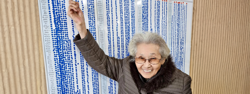 Local church deaconess Yoo HaeYeon, 92, smiles as she points to her Bible reading chart. Daily Bible reading is one of her secrets to staying healthy, she said. [Photo: Northern Asia-Pacific Division]