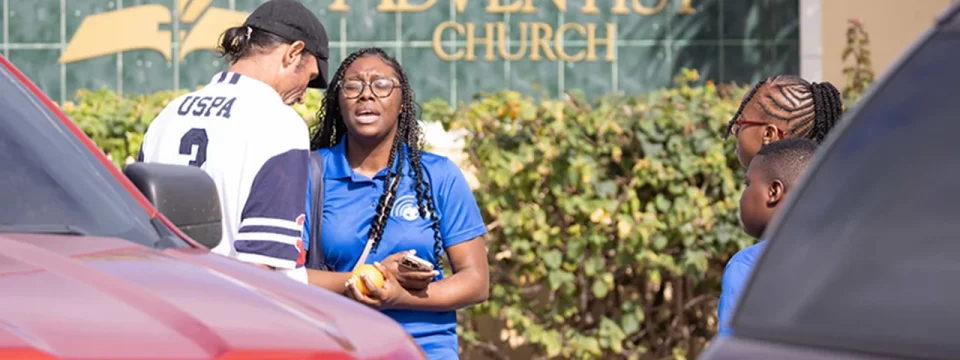 Durnique Bostwick (center) of the Centreville Seventh-day Adventist Church prays for a man who was walking by and requested prayer in Nassau, The Bahamas, on March 16. [Photo: John Garcia/ATCU]